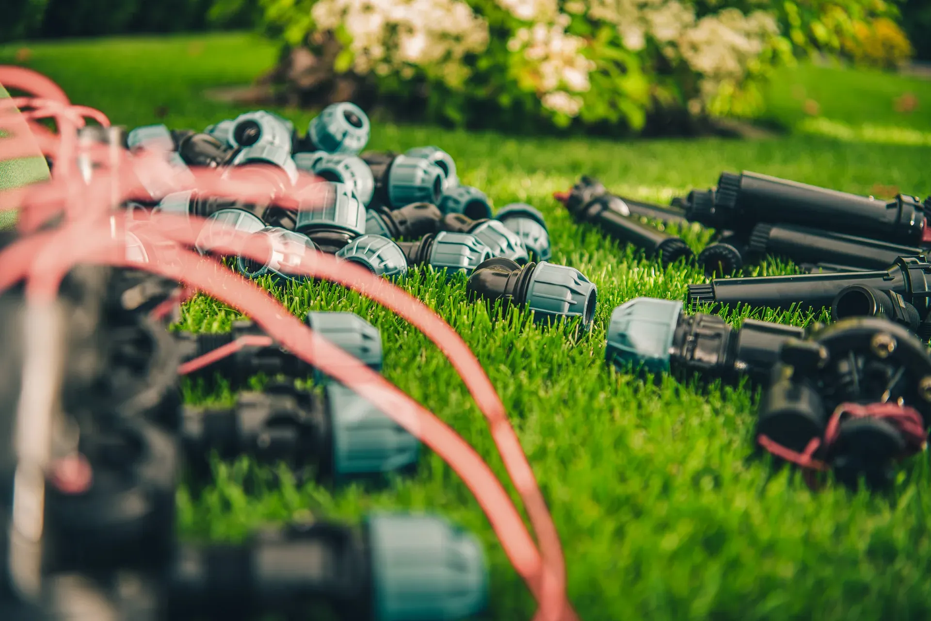Verschraubungen und Versenkregner einer Gartenbewässerung auf Rasen